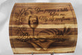 Wooden cutting board with engraved design of a wine glass, bread, and grapes, along with text.