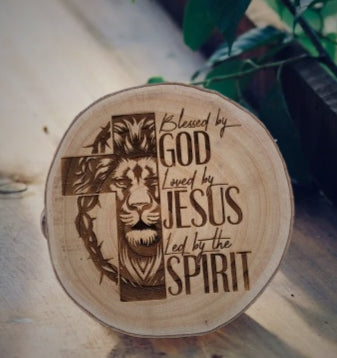 Wooden plaque with engraved text and religious symbols on a natural background