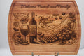 Wooden cutting board with engraved wine and food-themed design and text.